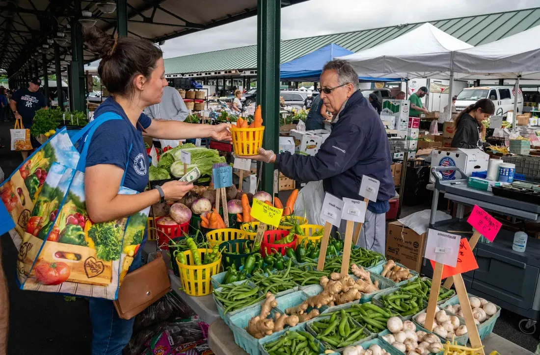 A person buying carrots at the Regional Farmers Market.